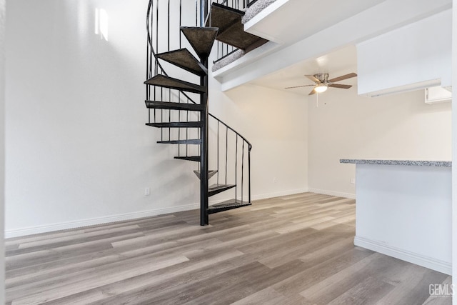 stairway with hardwood / wood-style flooring and ceiling fan