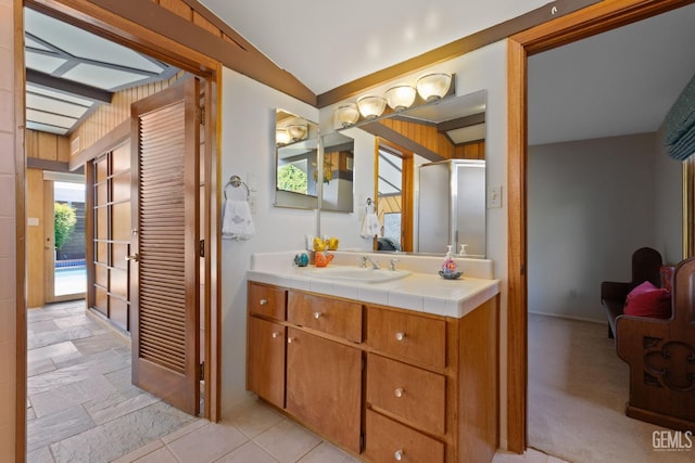 bathroom featuring a stall shower, vaulted ceiling, and vanity