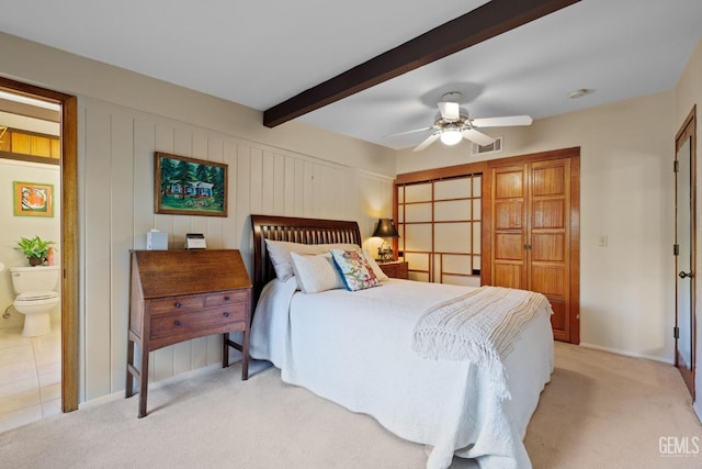 bedroom featuring connected bathroom, visible vents, beamed ceiling, and light carpet