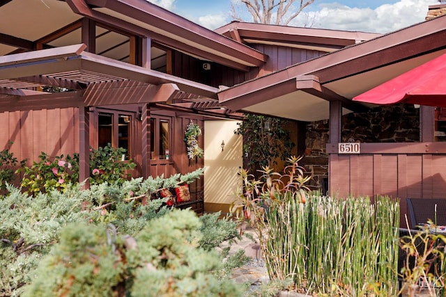 view of property exterior featuring board and batten siding and a pergola