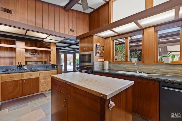 kitchen with ceiling fan, wood walls, a sink, brown cabinets, and black appliances