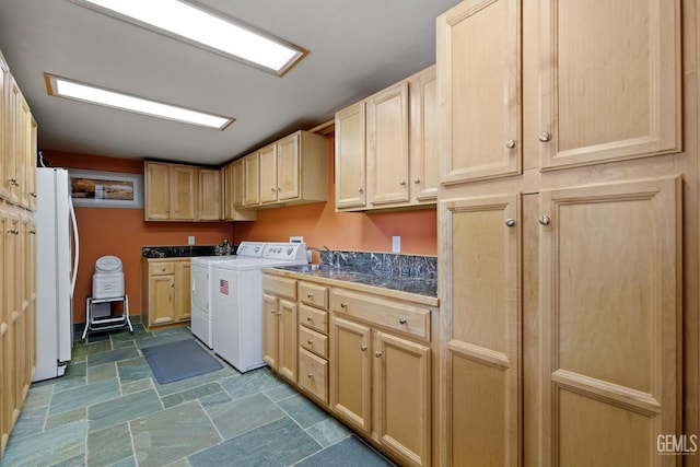 clothes washing area with cabinet space, stone finish flooring, and washer and dryer