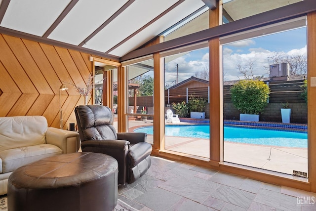 interior space featuring vaulted ceiling, wood walls, and stone tile floors