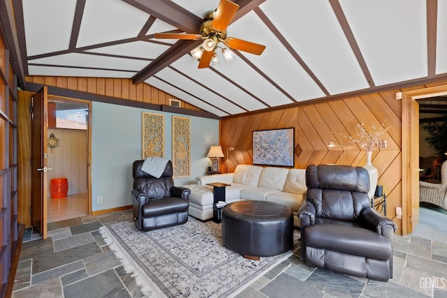 living room with lofted ceiling with beams, wooden walls, ceiling fan, and stone tile floors