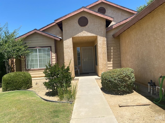 6208 Stonegate Dr, Bakersfield, CA 93306 - view of exterior entry with stucco siding and a lawn