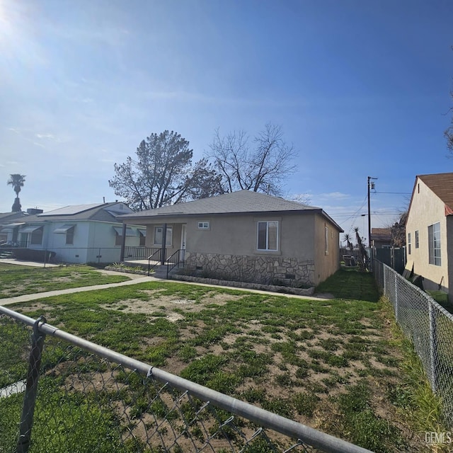 145 T St, Bakersfield, CA 93304 - view of front of house with stucco siding, a front yard, crawl space, fence private yard, and stone siding
