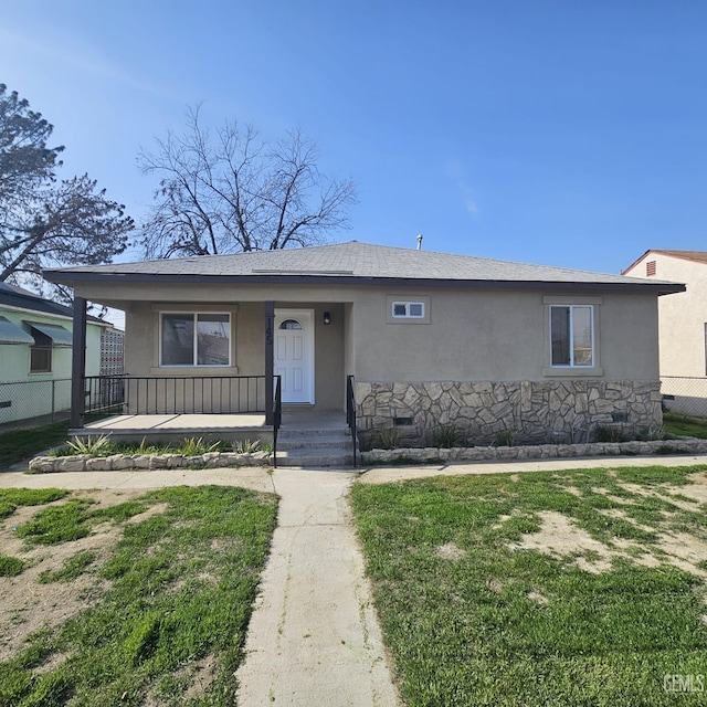 view of front of property with covered porch, fence, roof with shingles, crawl space, and stucco siding