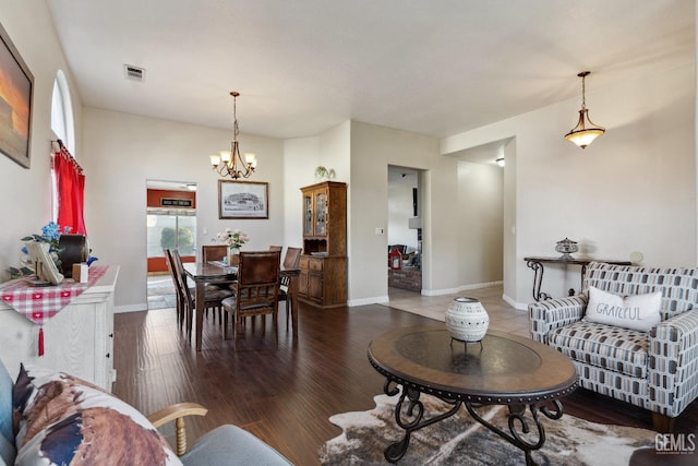 living area featuring a chandelier, visible vents, baseboards, and wood finished floors