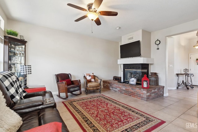 tiled living area featuring ceiling fan, a fireplace, and baseboards