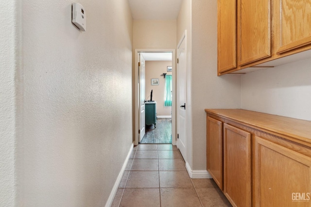 corridor featuring baseboards and light tile patterned flooring