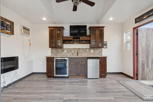 kitchen with wine cooler, a wall mounted AC, light wood-style flooring, and baseboards