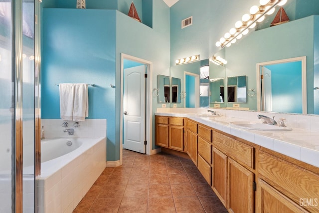 bathroom with a garden tub, tile patterned flooring, a sink, visible vents, and double vanity