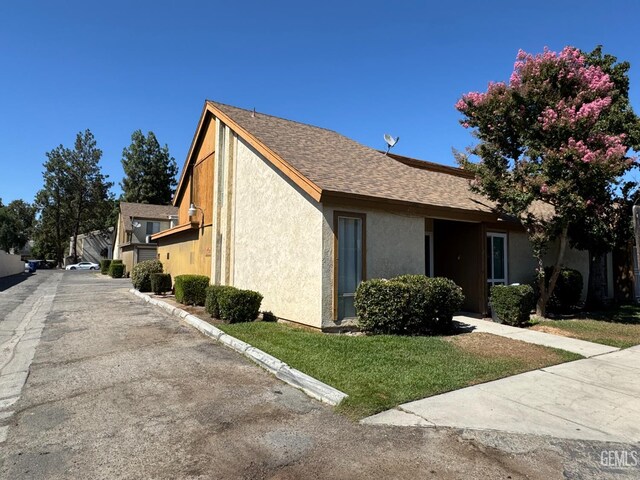 5001 Belle Ter Unit 12, Bakersfield, CA 93309 - view of side of property featuring stucco siding, roof with shingles, and a lawn