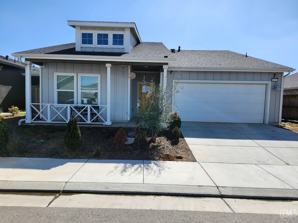 view of front of house featuring a porch, a garage, driveway, roof with shingles, and board and batten siding