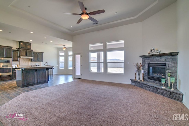unfurnished living room with ceiling fan, a raised ceiling, recessed lighting, dark carpet, and baseboards