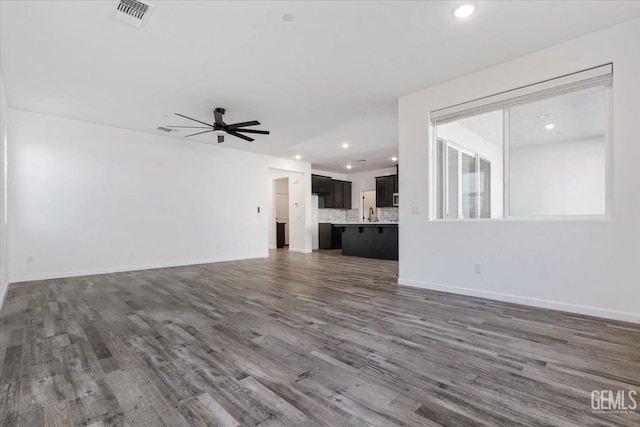 unfurnished living room featuring dark wood-type flooring and ceiling fan