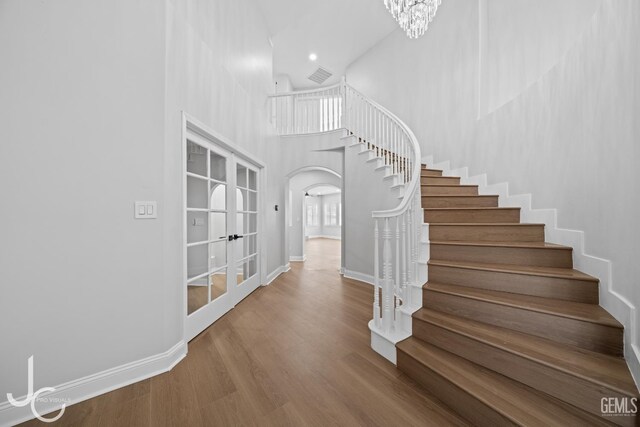 11009 Bright Water Way, Bakersfield, CA 93311 - stairway with french doors, arched walkways, a high ceiling, baseboards, and wood finished floors