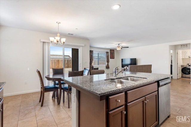 kitchen featuring dishwasher, sink, washer / clothes dryer, an island with sink, and ceiling fan with notable chandelier