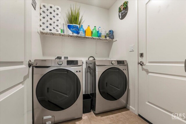 clothes washing area with independent washer and dryer and light tile patterned floors