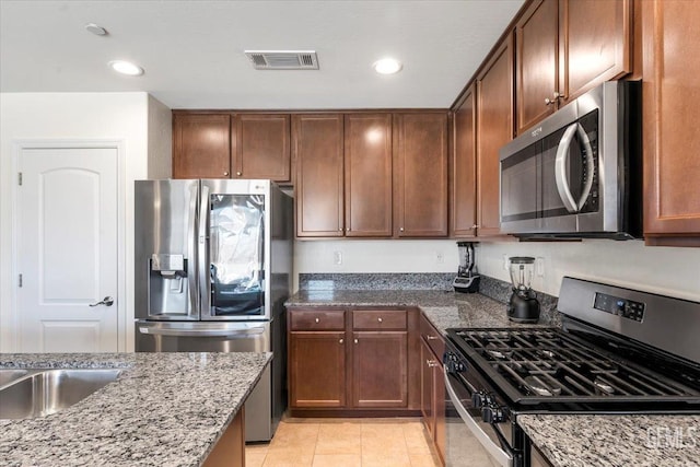 kitchen featuring stone counters, light tile patterned flooring, and stainless steel appliances