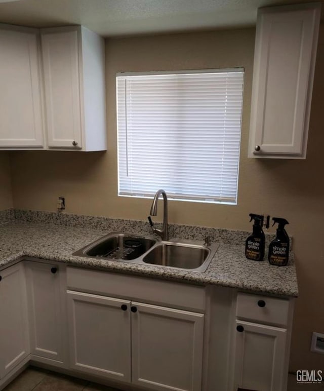 kitchen featuring white cabinetry, sink, and light stone counters