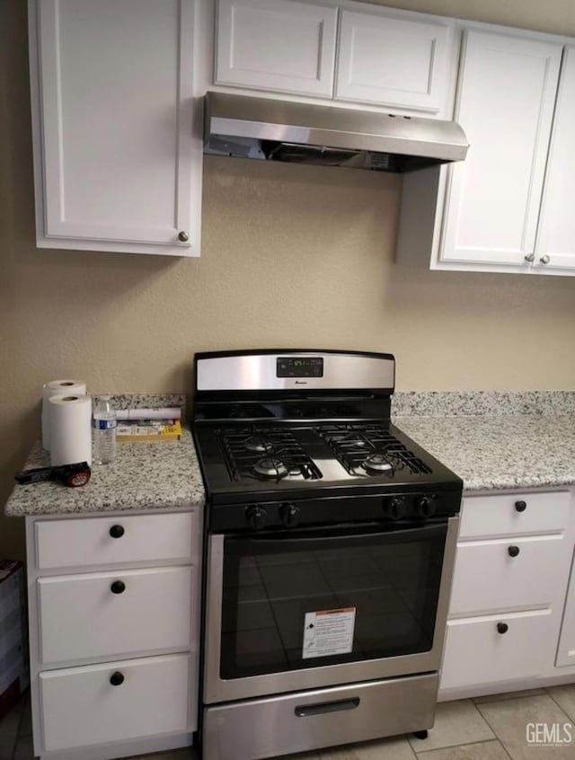 kitchen featuring stainless steel gas stove, light stone countertops, and white cabinets