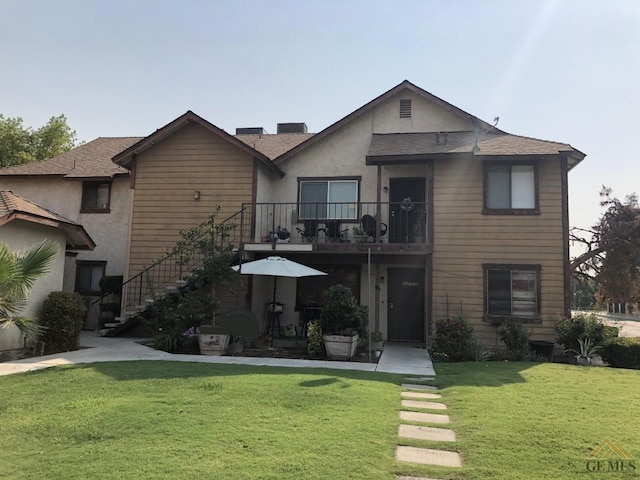 view of front of house with a balcony and a front lawn