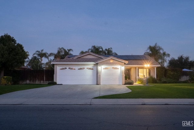 single story home with solar panels, a garage, and a yard