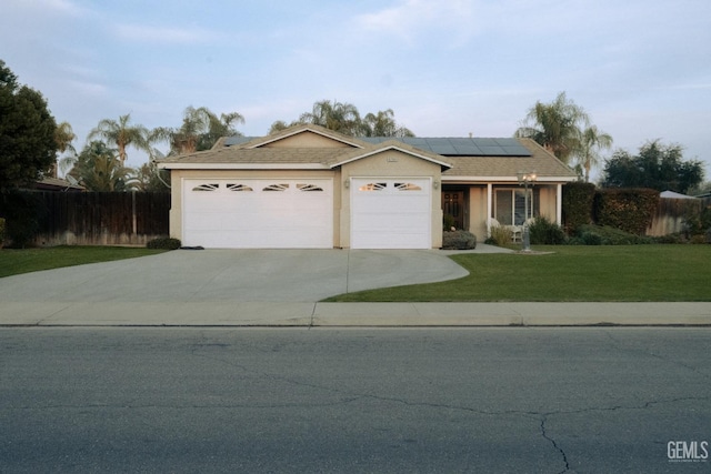 single story home with a front yard, solar panels, and a garage