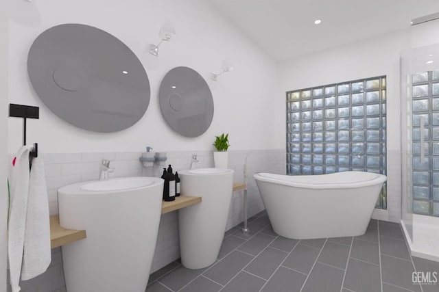 bathroom with a wainscoted wall, a freestanding bath, tile walls, and tile patterned floors