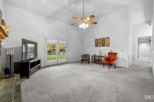 sitting room featuring carpet flooring, ceiling fan, and a towering ceiling