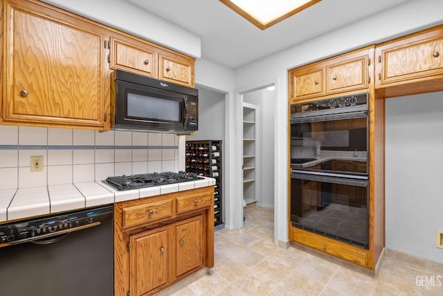 kitchen with tile countertops, black appliances, and tasteful backsplash