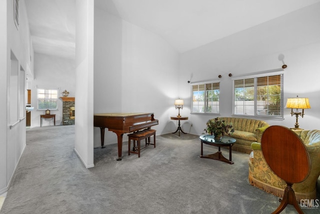 carpeted living area featuring high vaulted ceiling and a fireplace