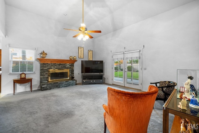 carpeted living area featuring ceiling fan, french doors, a brick fireplace, and a towering ceiling