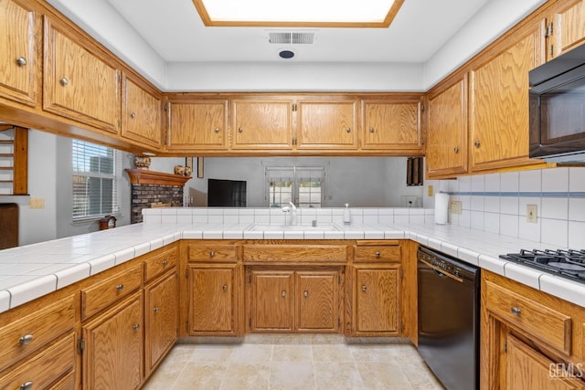 kitchen featuring black appliances, brown cabinets, and a sink