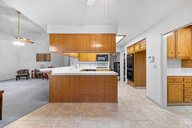 kitchen featuring tile counters, light colored carpet, a ceiling fan, a peninsula, and black appliances