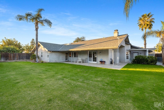 back of property with a yard, a patio area, and fence