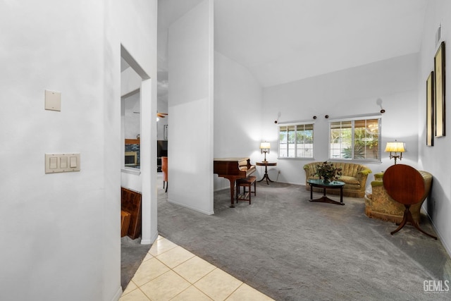 tiled living area featuring high vaulted ceiling and carpet