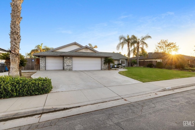 view of front of home featuring an attached garage, concrete driveway, a front yard, and fence