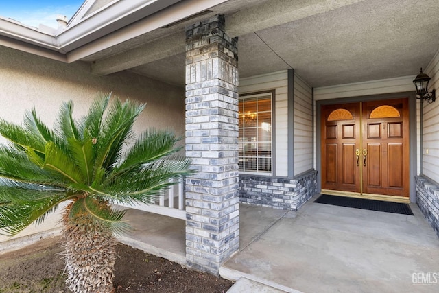 doorway to property with stone siding and a porch