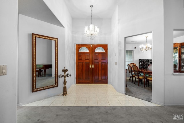 entryway featuring tile patterned flooring, carpet flooring, a towering ceiling, and an inviting chandelier