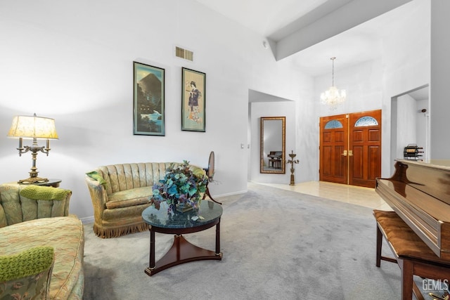 carpeted living room with baseboards, a towering ceiling, visible vents, and an inviting chandelier