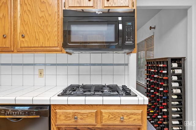 kitchen featuring black appliances, tasteful backsplash, and tile counters