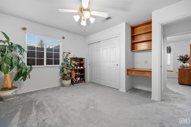 interior space with ceiling fan, carpet flooring, visible vents, a closet, and built in study area