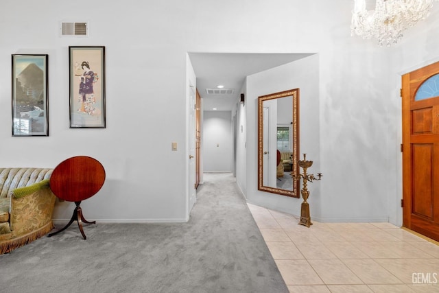 foyer entrance with visible vents, a notable chandelier, light carpet, and light tile patterned floors