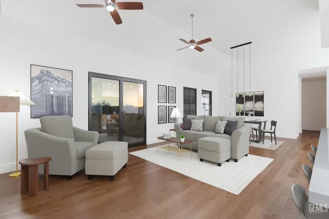 living room with high vaulted ceiling, a ceiling fan, baseboards, and wood finished floors