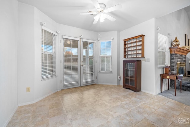 empty room with a fireplace, ceiling fan, and baseboards