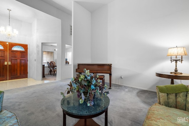 carpeted living room featuring baseboards, a high ceiling, and a chandelier