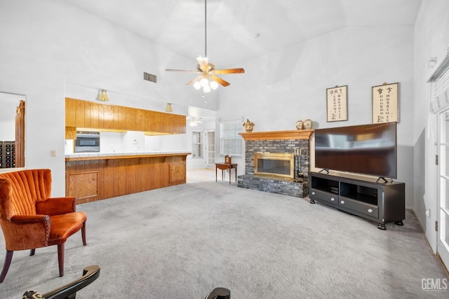 living area featuring ceiling fan, high vaulted ceiling, light colored carpet, visible vents, and a brick fireplace