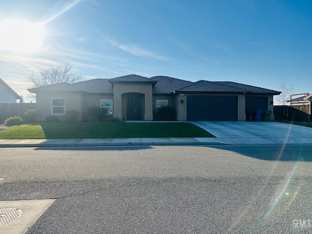 view of front facade with an attached garage, a tile roof, fence, concrete driveway, and stucco siding